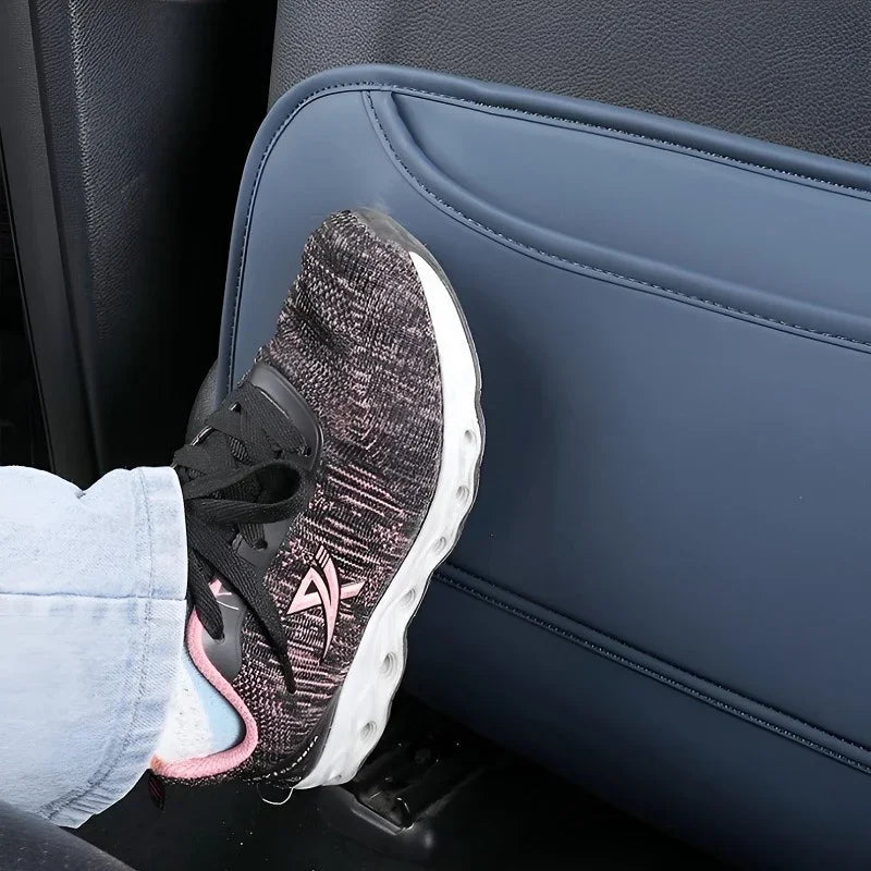 A foot wearing a black and pink athletic sneaker rests against a blue leather car seat protector.