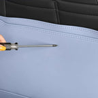 Close-up of a screwdriver testing the durability of light blue synthetic leather car seat covers.