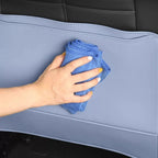 A hand cleaning a durable, light blue leather car seat cover with a microfiber cloth.
