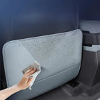 Waterproof grey leather car seat back protector being wiped clean with a soft cloth.