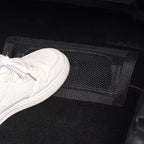 Black mesh storage net organizer installed on the vehicle floor for secure item storage.