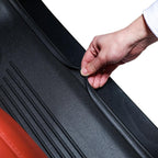 A person's hand demonstrating the flexible, durable black rubber material of a car floor mat.