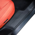 Black textured protective door sill plate installed on a vehicle interior with red leather seats.