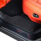 Black heavy-duty rubber door sill protector installed in a car with orange leather seats.