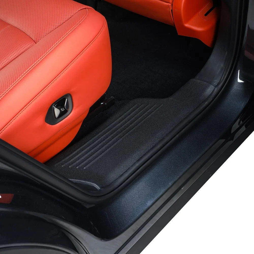 Black textured protective door sill plate installed on a car with red leather seats.