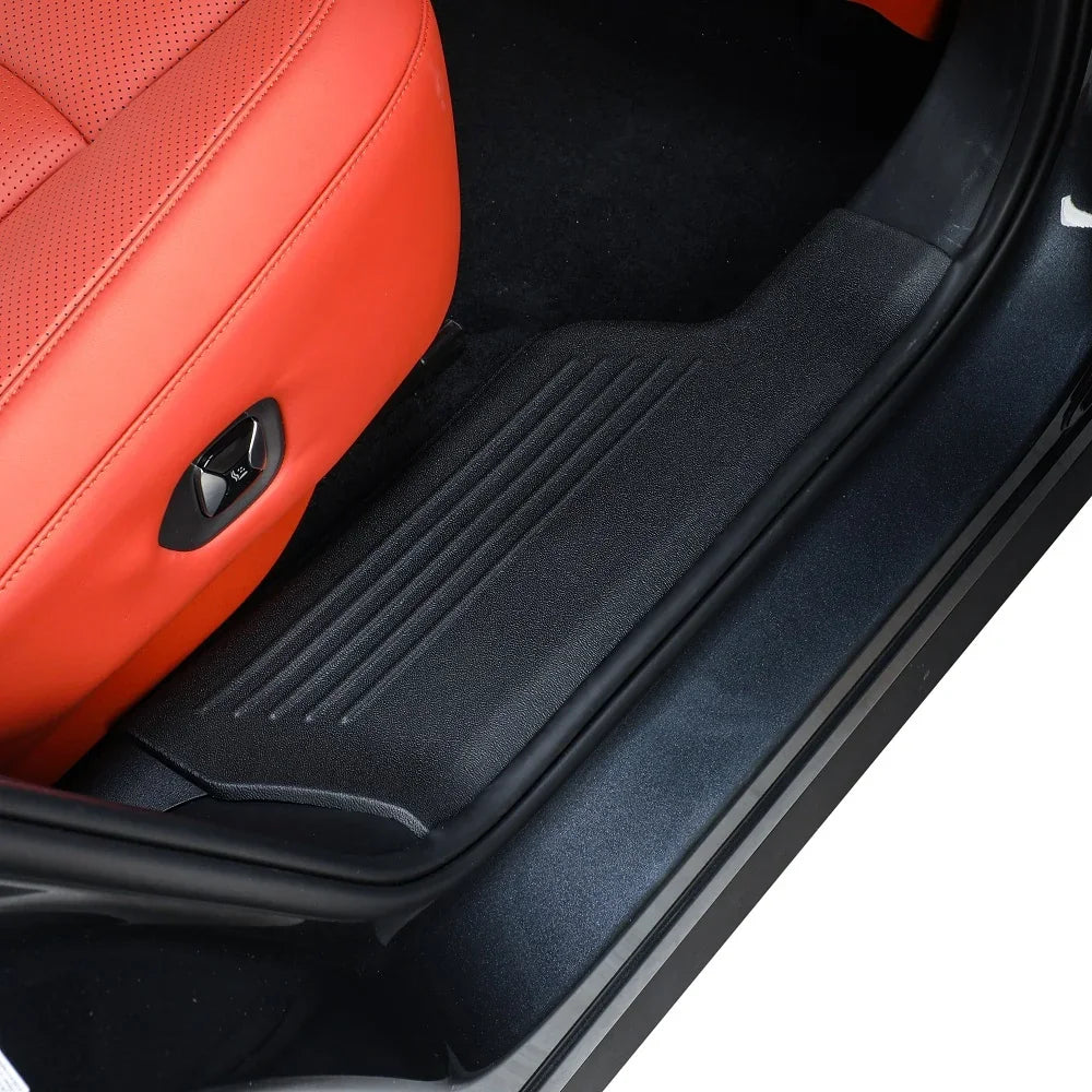 Black heavy-duty rubber door sill protector installed on a car with red leather seats