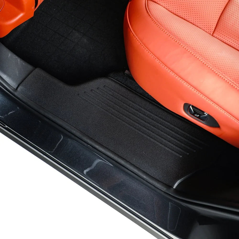 Black textured TPE floor mats and orange leather car seats for premium interior protection.