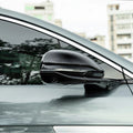 Glossy black aerodynamic side mirror cover with integrated LED indicator for a grey car.