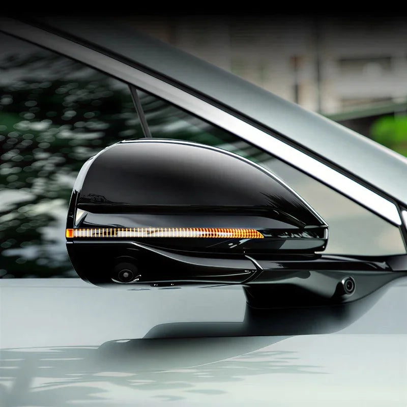 Glossy black side mirror cover with integrated LED turn signal indicator for a modern car.