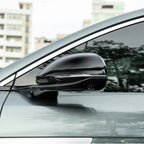 Glossy black side mirror cover with integrated LED turn signal for a grey car.