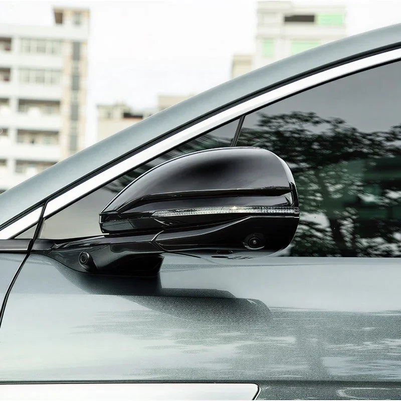 Glossy black side mirror cover with integrated LED turn signal for a grey car.