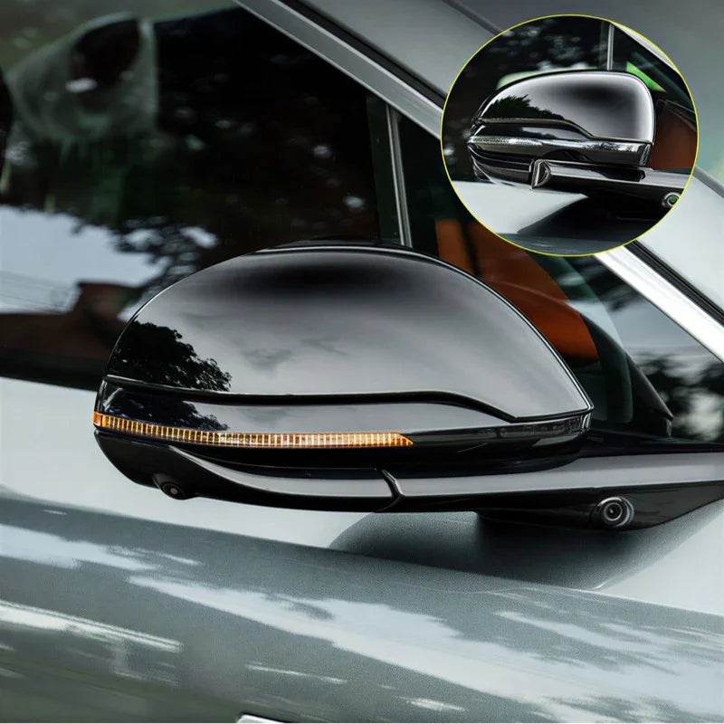Glossy black carbon fiber side mirror cover with integrated LED turn signal indicator.