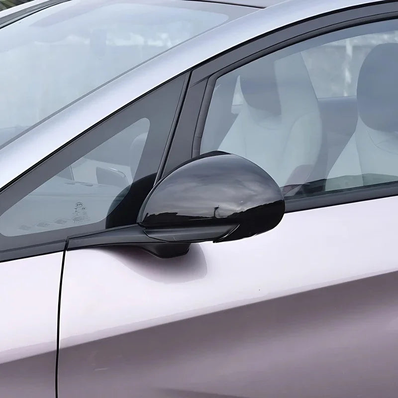 Glossy black side mirror cover accessory installed on a silver vehicle.