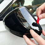 Glossy black protective film being applied to a car side mirror housing.