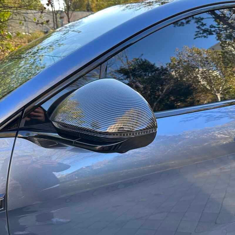 Carbon fiber side mirror cover in glossy black for a sleek, sporty automotive look.