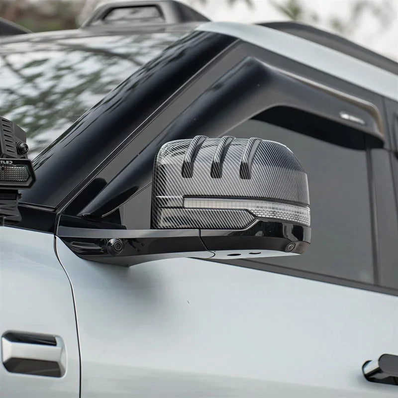 Carbon fiber texture side mirror cover with a sporty ribbed design for a white vehicle.