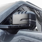 Matte black car side mirror cover with sleek aerodynamic ridges and integrated LED signal light