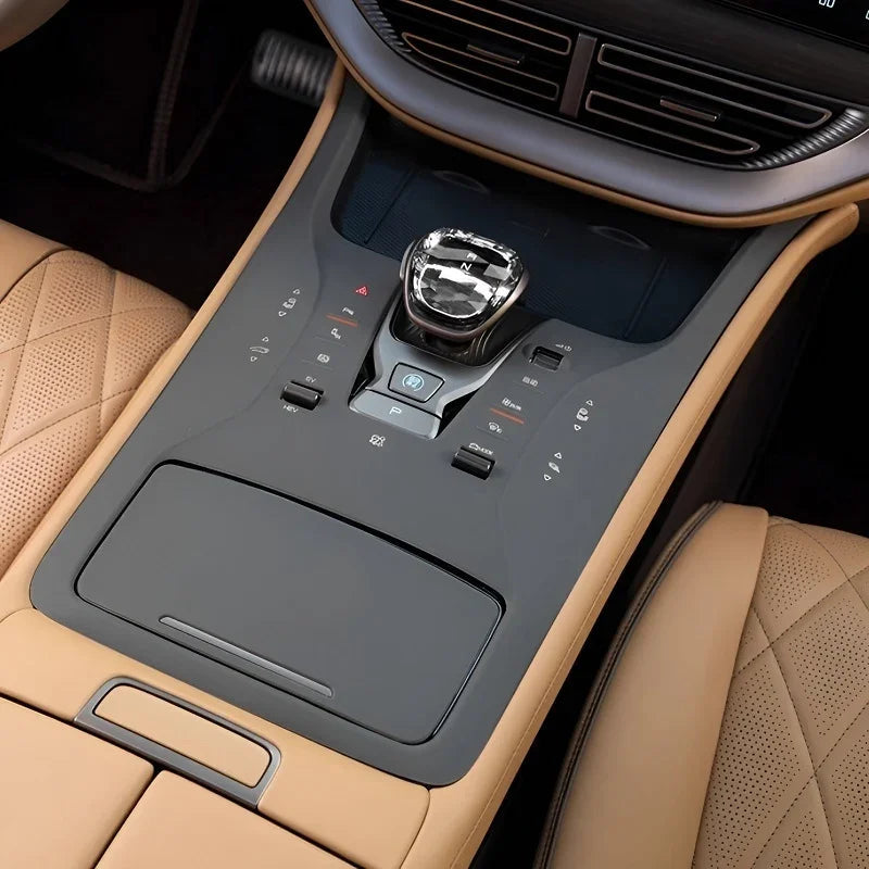 Detailed view of a luxury car center console with tan leather and black matte finishes.