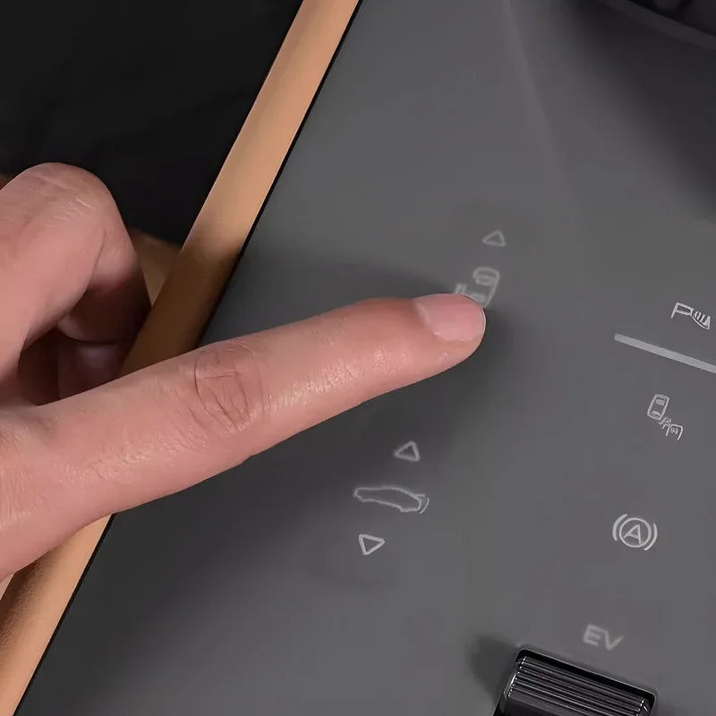 A finger pressing a sleek, matte black touch control button on a modern car dashboard panel.