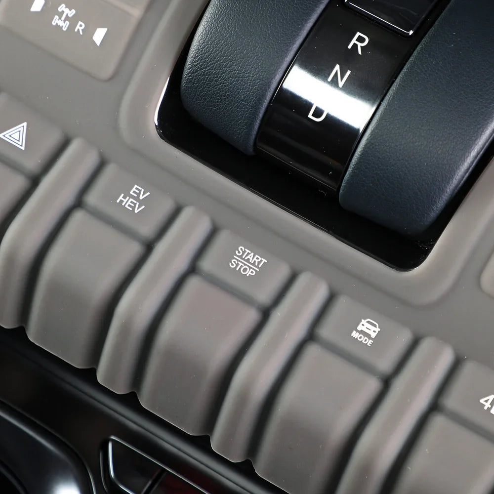 Close-up of a grey matte center console with EV, HEV, and Start/Stop buttons and a black gear shifter.