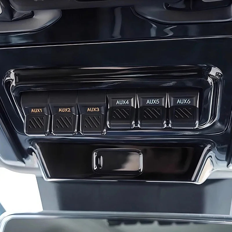 Glossy black interior panel featuring six labeled AUX auxiliary switches for vehicle accessories.