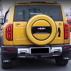 Rear view of a yellow SUV featuring a custom black and silver spare tire cover and matching mud flaps.