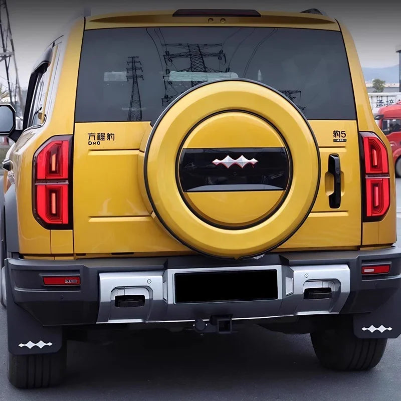 Rear view of a yellow SUV featuring a custom black and silver spare tire cover and matching mud flaps.