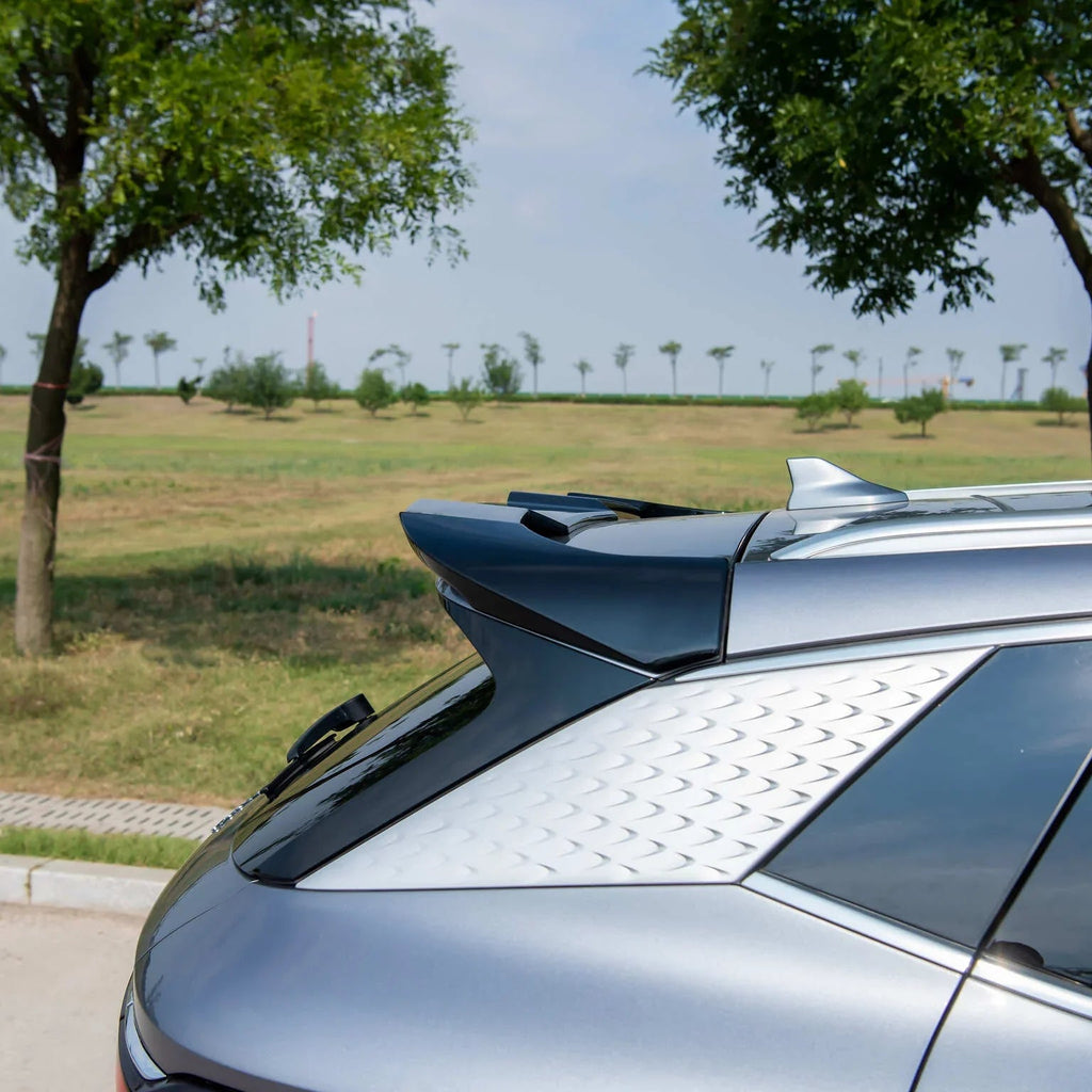 Rear view of a silver BYD car featuring a sleek black spoiler and textured silver trim.