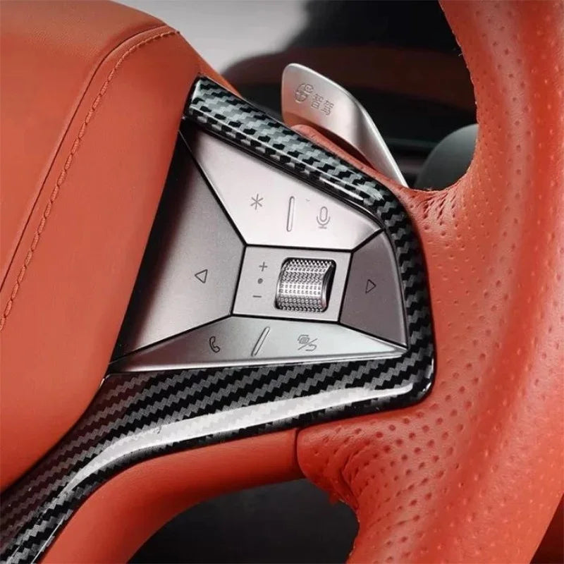 Close-up of a BYD steering wheel featuring carbon fiber trim and orange perforated leather.
