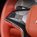 Close-up of a BYD steering wheel with orange leather and carbon fiber trim accents.