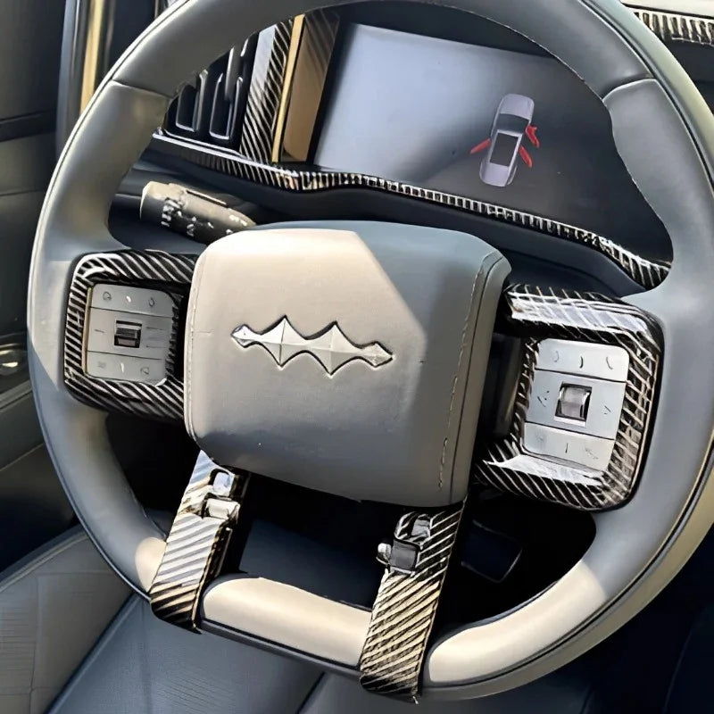 Grey leather steering wheel with black carbon fiber trim and integrated control buttons.