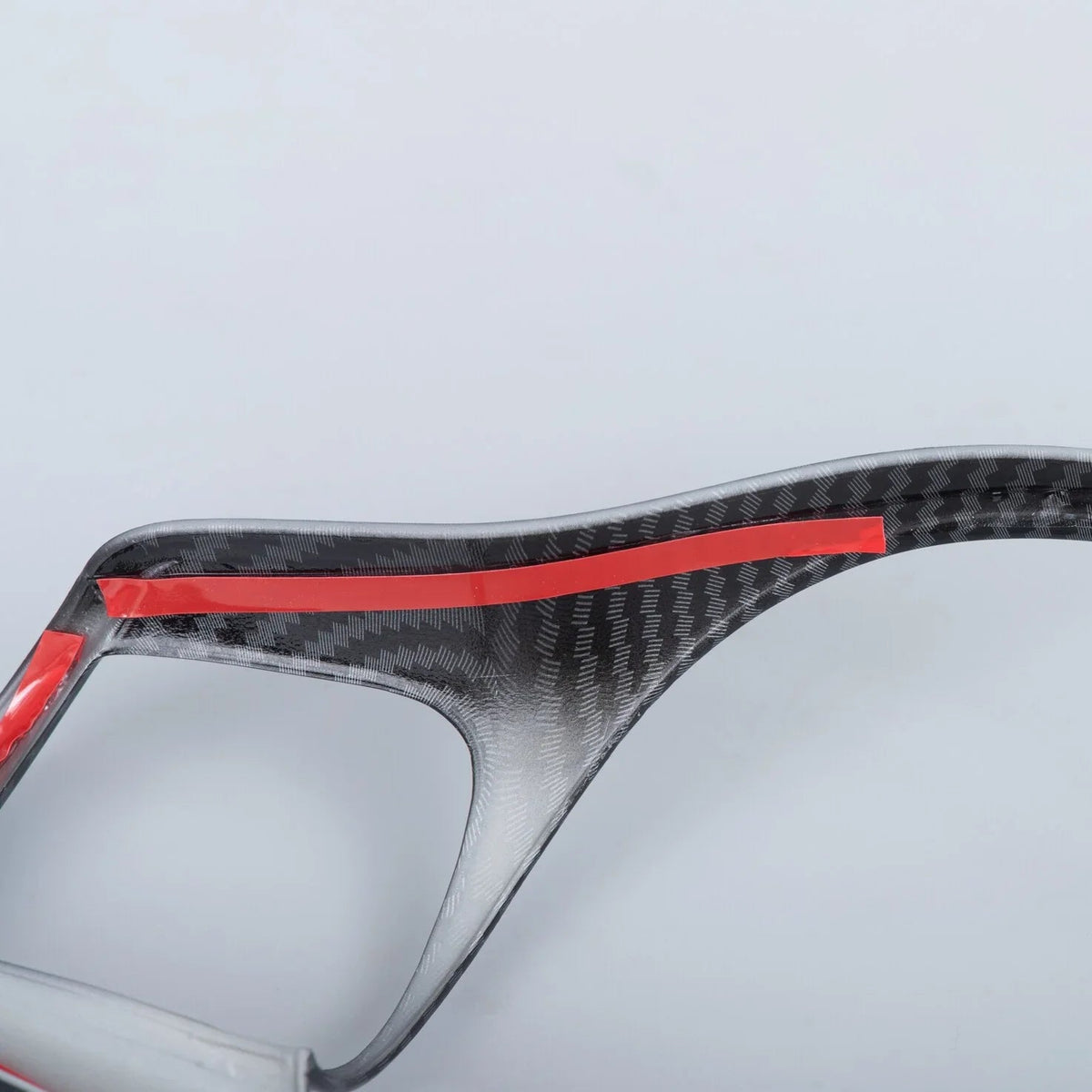 Grey carbon fiber car accessory with red protective tape accents