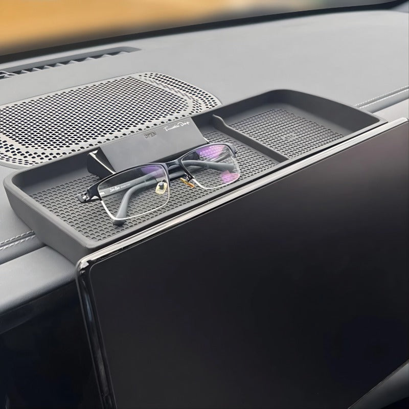 Matte black textured dashboard storage tray for BYD, holding glasses near the screen.
