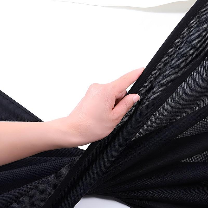 Durable black mesh car sunshade fabric being held to show its fine texture and flexibility.
