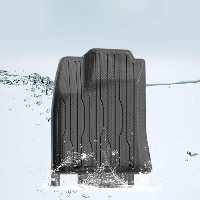 Black waterproof textured rubber car floor mat being splashed with water.