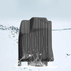 Black waterproof textured rubber car floor mat being splashed with water.