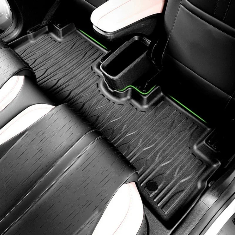 Black textured TPE car floor mats with vibrant green edge stitching for BYD interior protection.