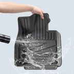 Waterproof black TPE car floor mat being rinsed, featuring a durable textured design.