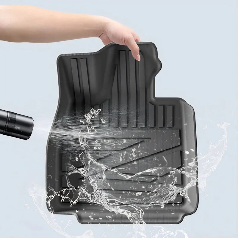 Waterproof black TPE car floor mat being rinsed, featuring a durable textured design.