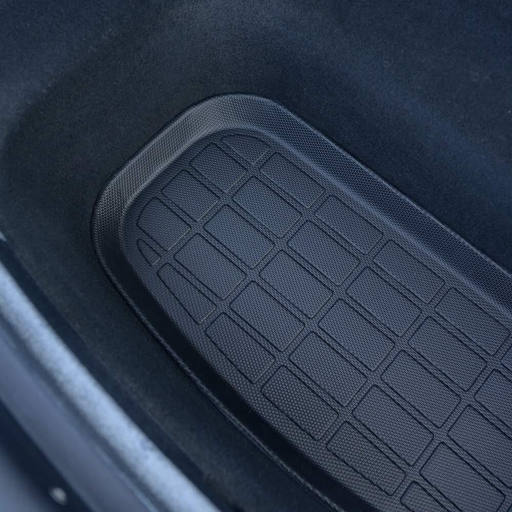 Close-up of a black textured rubber car floor mat with a grid pattern for durability.