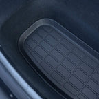 Close-up of a black textured rubber car floor mat with a grid pattern for durability.