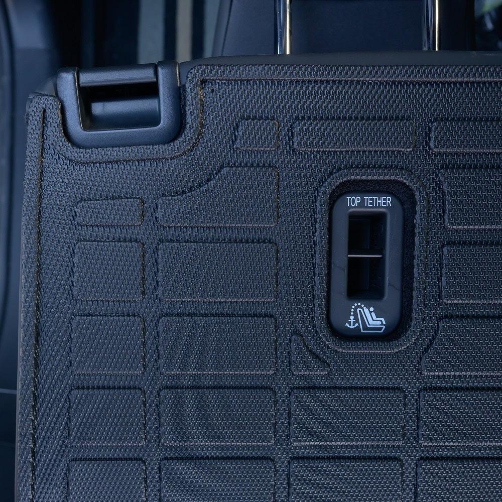 Black textured TPE car seat back protector with integrated top tether access port.
