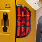 Carbon fiber texture black trim surrounding bright red LED taillight on a yellow car.