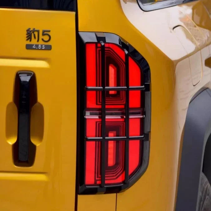 Rugged black protective grille covering a red LED taillight on a yellow vehicle.