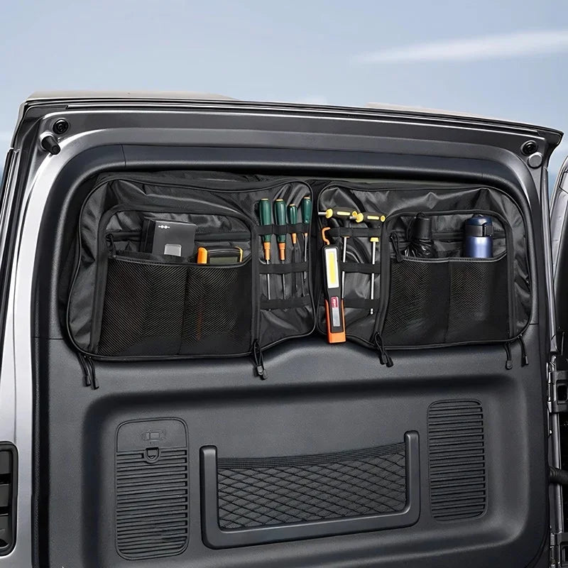 Black heavy-duty fabric car trunk organizer hanging on a vehicle rear door, storing tools.