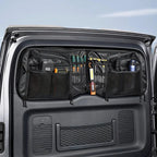 Black heavy-duty fabric car trunk organizer hanging on a vehicle rear door, storing tools.