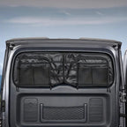 Black heavy-duty fabric organizer with mesh pockets installed on a grey vehicle rear door.