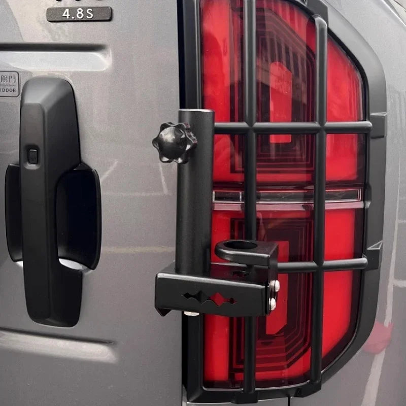 Matte black metal tail light guard with protective grille for a silver vehicle.