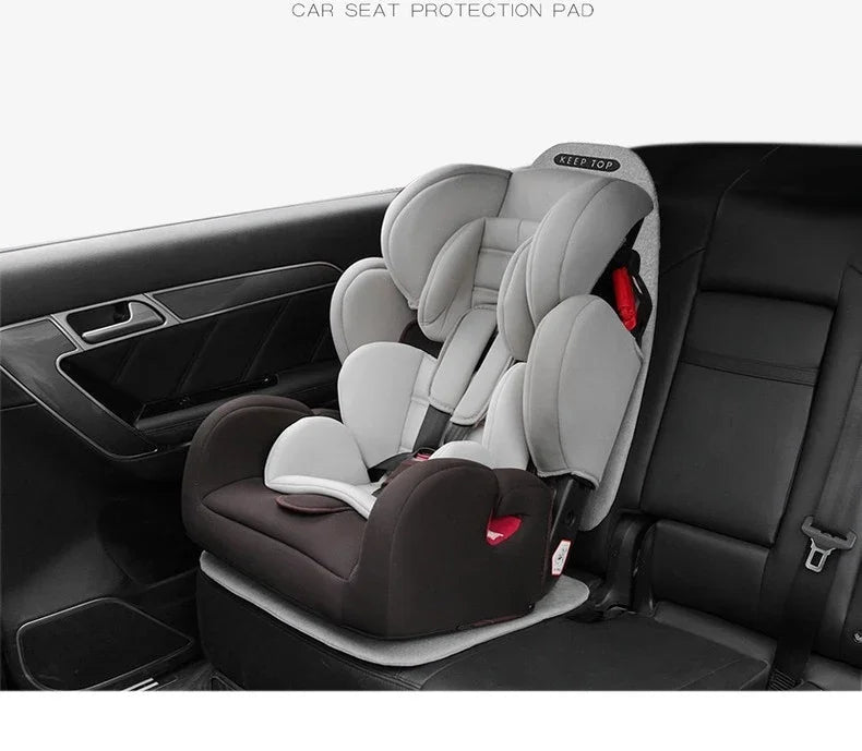 Grey and black car seat protection pad installed under a child safety seat in a vehicle.
