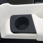 Black matte textured cup holder integrated into white premium car interior trim.